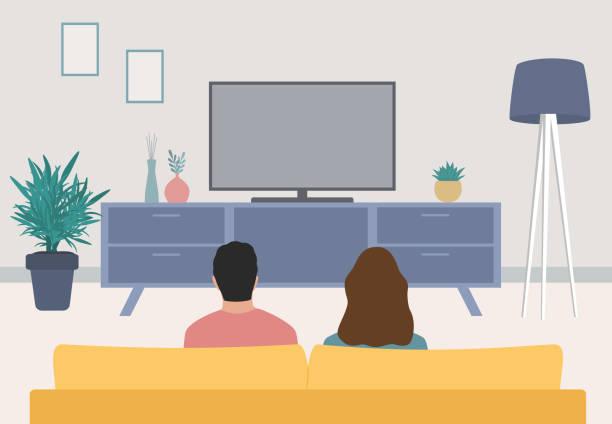 Rear View Of Young Couple Sitting On Sofa And Watching Television