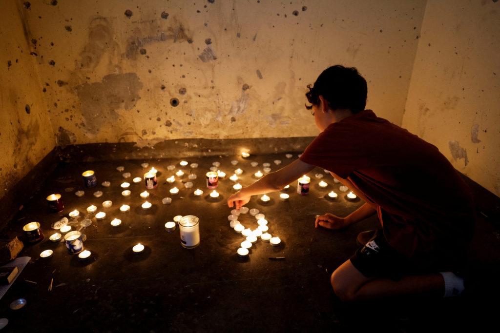 A boy lights memorial candles inside a bomb shelter in which people were killed during the deadly October 7 attack by Hamas from Gaza, on the first anniversary since the attack, near Kibbutz Mefalsim in southern Israel, October 7, 2024. REUTERS/Amir Cohen     TPX IMAGES OF THE DAY