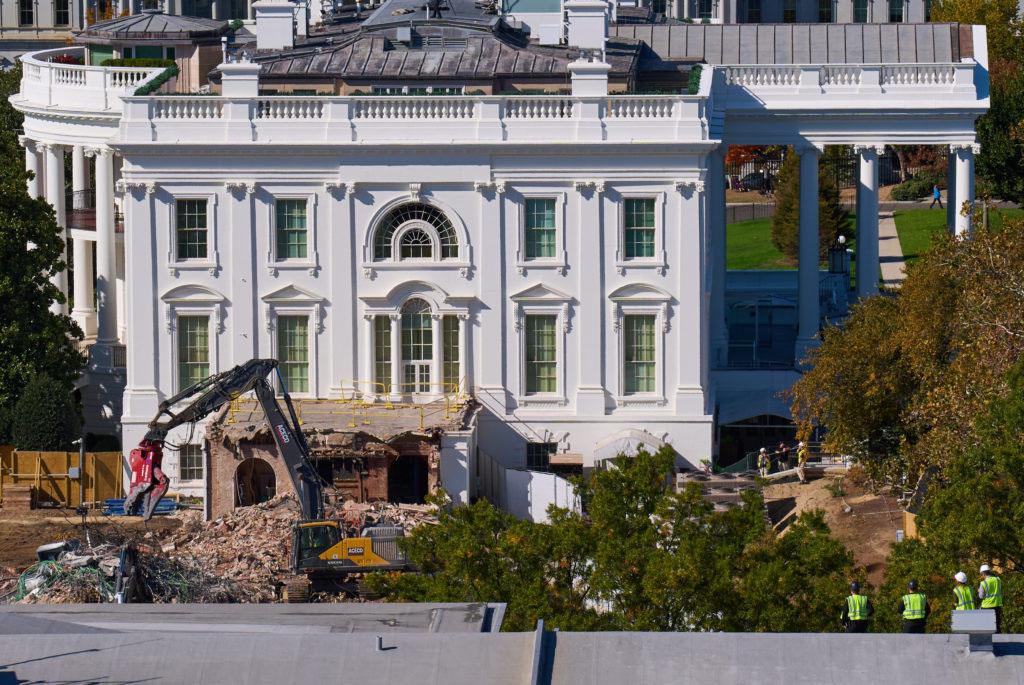 Construction workers, bottom right, atop the U.S. Treasury, watch as work continues on a largely demolished part of the East Wing of the White House, Thursday, Oct. 23, 2025, in Washington, before construction of a new ballroom. (AP Photo/Jacquelyn Martin)