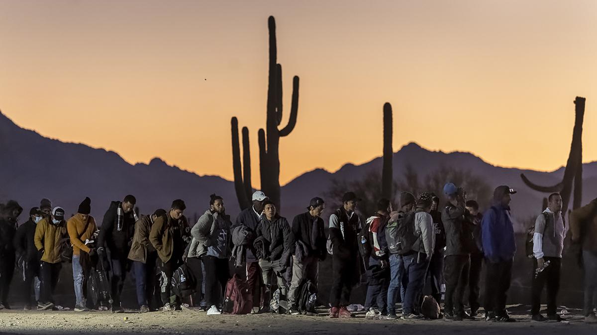 LUKEVILLE, ARIZONA - DECEMBER 07: Immigrants line up at a remote U.S. Border Patrol processing center after crossing the U.S.-Mexico border on December 07, 2023 in Lukeville, Arizona. A surge of immigrants illegally passing through openings cut by smugglers into the border wall has overwhelmed U.S. immigration authorities, causing them to shut down several international ports of entry so that officers can help process the new arrivals. (Photo by John Moore/Getty Images)